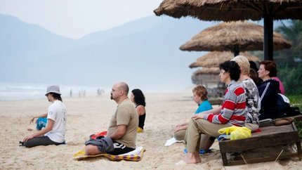 Du khách ngồi thiền trên bãi biển vào buổi sáng