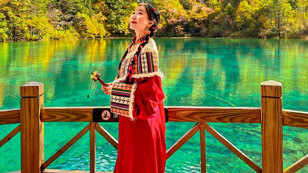 Cô gái trong trang phục dân tộc Tạng cầm pháp luân bên hồ