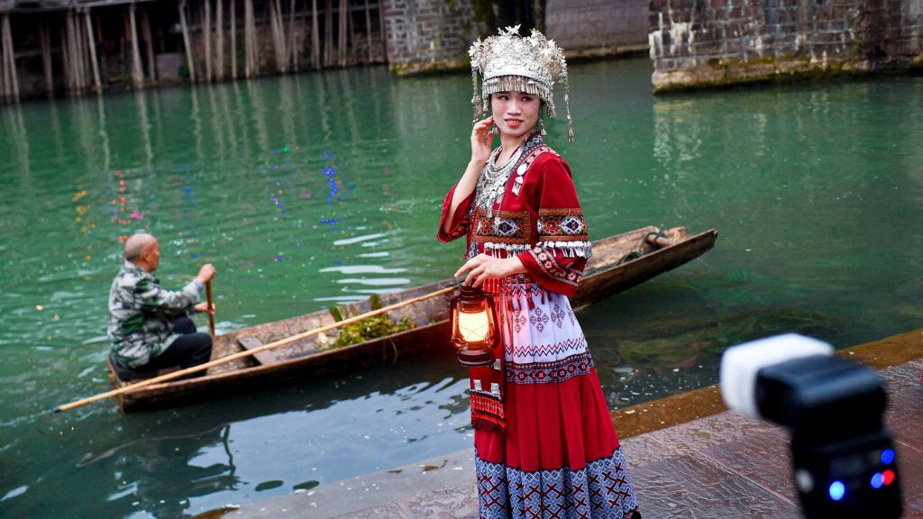 Du khách mang trang phục dân tộc thả dáng chụp ảnh tại bến thuyền độc mộc