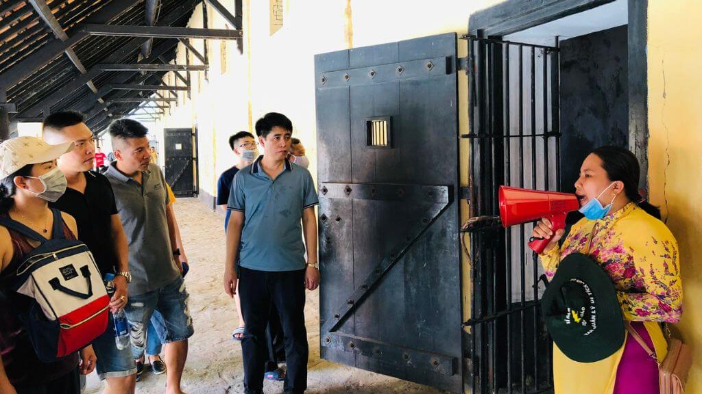 Du khách nghe thuyết minh về di tích Trại tù